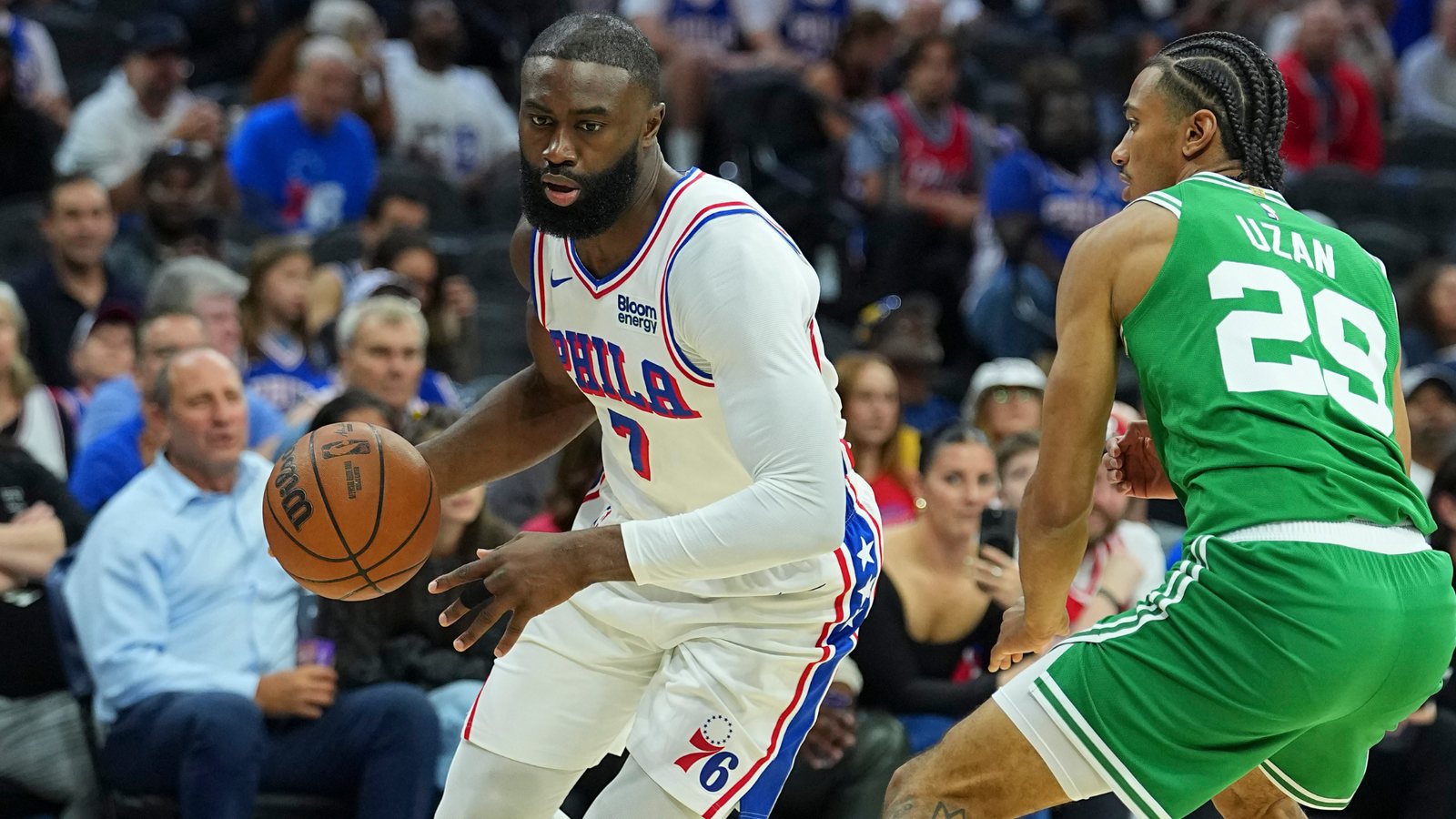 Jaylen Brown, in a white 76ers home uniform, dribbles against a defender in a green Celtics uniform in Philadelphia.